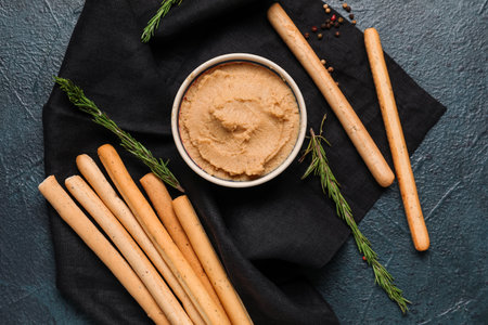 Bowl with tasty hummus and Italian Grissini on dark backgroundの写真素材
