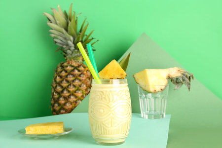 Glass of tasty pineapple smoothie with straws on color background