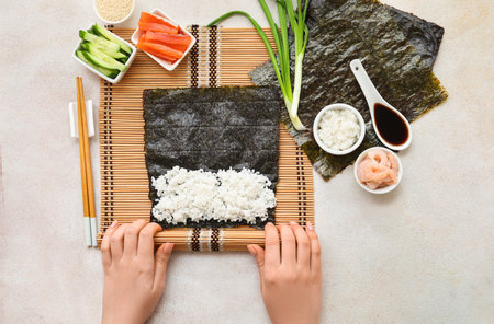 Woman preparing sushi rolls on light backgroundの写真素材