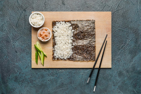 Wooden board with nori and ingredients for preparing sushi rolls on dark backgroundの写真素材