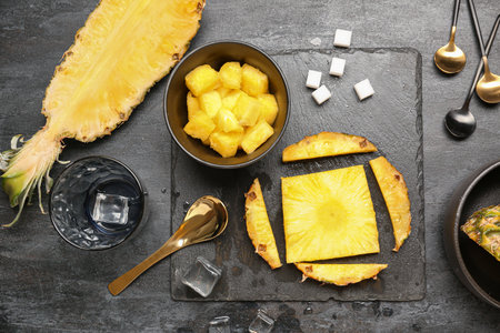 Composition with fresh cut pineapple, sugar and ice cubes on black backgroundの写真素材
