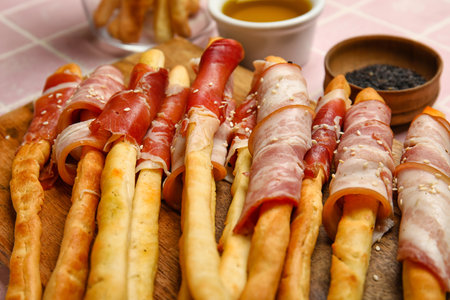 Wooden board of tasty Italian Grissini with bacon on table, closeupの写真素材