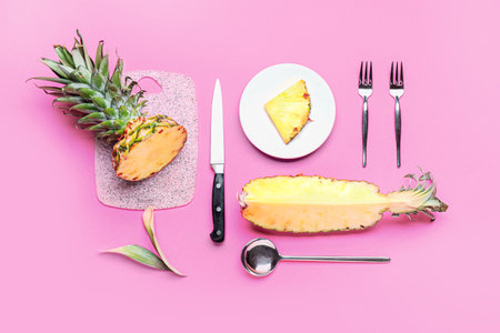 Composition with fresh ripe pineapple, board and cutlery on pink backgroundの写真素材