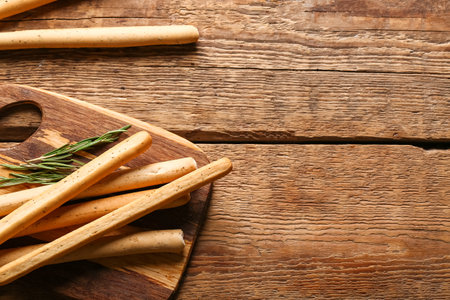Board with tasty Italian Grissini on wooden background, closeupの写真素材
