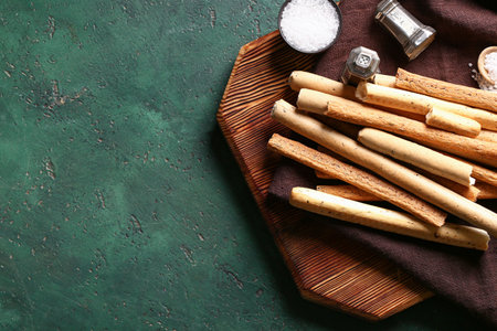 Wooden board with tasty Italian Grissini on green backgroundの写真素材