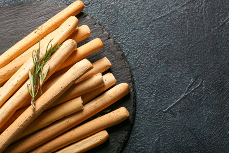 Slate board with tasty Italian Grissini on dark background, closeupの写真素材