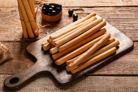 Board with tasty Italian Grissini on wooden backgroundの写真素材
