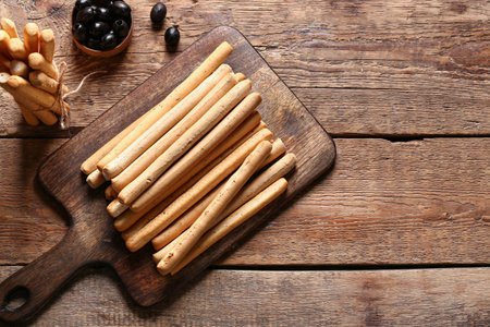 Board with tasty Italian Grissini on wooden backgroundの写真素材