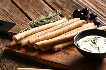 Board with tasty Italian Grissini on wooden backgroundの写真素材