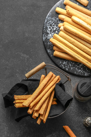Slate board and basket with tasty Italian Grissini on dark backgroundの写真素材