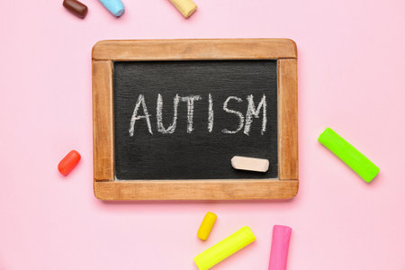 Chalkboard with word AUTISM and plastic on pink backgroundの写真素材