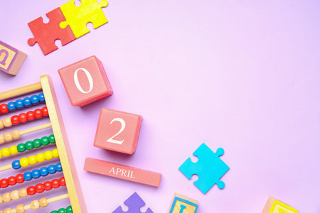 Date of World Autism Awareness Day with baby toys on lilac background