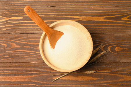 Bowl with raw semolina on wooden backgroundの写真素材