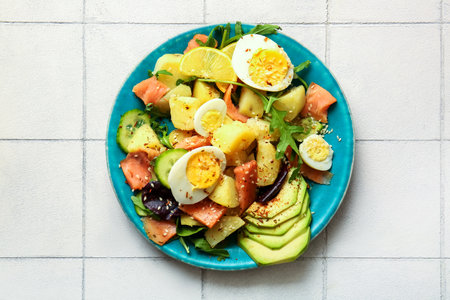 Plate of tasty potato salad with eggs and avocado on light background, top viewの写真素材