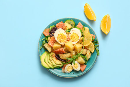 Plate of tasty potato salad with eggs and avocado on light blue background, top viewの写真素材