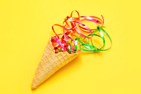 Composition with ice cream cone and confetti on yellow backgroundの写真素材