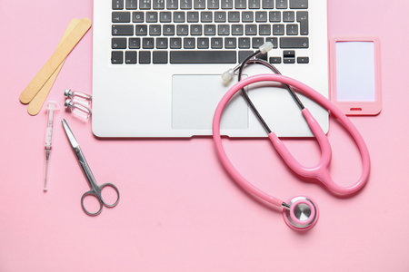 Stethoscope, laptop, badge and drugs on pink backgroundの写真素材