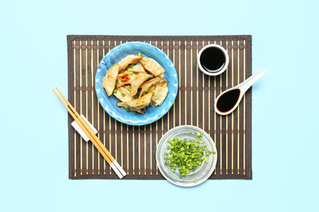 Plate with tasty Chinese jiaozi, onion and sauce on blue backgroundの写真素材