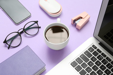 Composition with laptop, coffee, eyeglasses and notepad on purple background