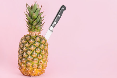 Fresh ripe pineapple with knife on pink backgroundの写真素材