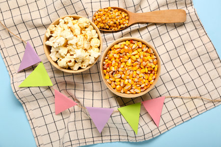 Bowls with spoon of corn, flags and napkin on blue background. Festa Junina (June Festival) celebrationの写真素材