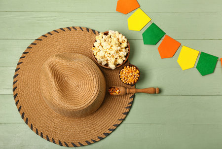 Bowls of corn with scoop, straw hat and flags on green wooden background. Festa Junina (June...