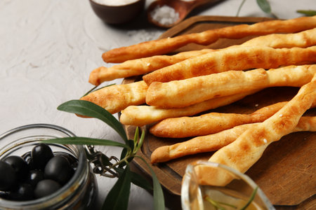 Wooden board with tasty Italian Grissini on light background, closeupの写真素材