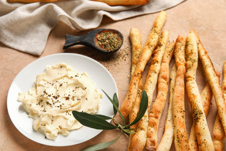 Tasty Italian Grissini and plate with butter on beige background, closeupの写真素材
