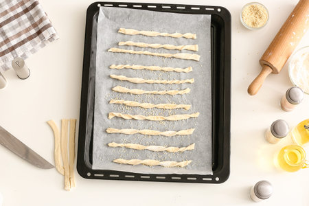 Baking sheet with Italian Grissini on white background