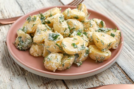 Plate of tasty Potato Salad with greens on light wooden backgroundの写真素材