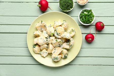 Plate of tasty Potato Salad with dill and parsley on green wooden backgroundの写真素材