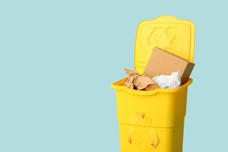 Container for garbage with paper on light blue background. Recycling conceptの写真素材