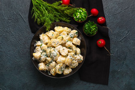 Bowl of tasty Potato Salad with greens on dark backgroundの写真素材