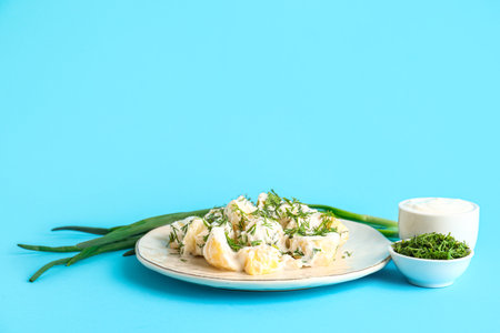 Plate of tasty Potato Salad with greens on blue backgroundの写真素材