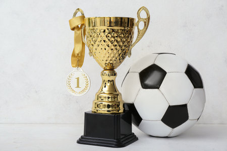 Gold cup with first place medal and soccer ball on light backgroundの写真素材