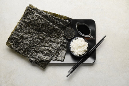 Nori sheets with rice, sesame seeds and sauce on light backgroundの写真素材