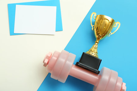 Blank card with gold cup and dumbbell on color backgroundの写真素材