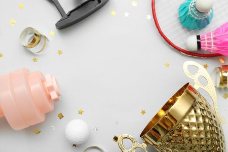 Frame made of gold cup with sports equipment and confetti on light backgroundの写真素材