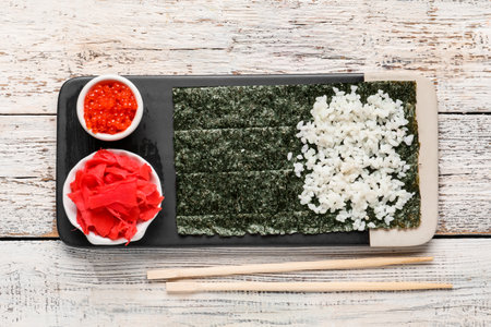 Board with nori and ingredients for preparing sushi rolls on light wooden backgroundの写真素材