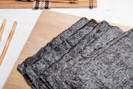 Wooden board with nori sheets on light background, closeupの写真素材
