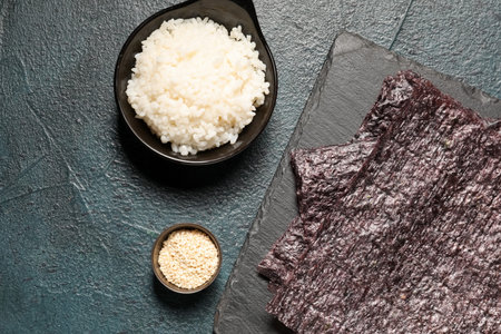 Slate board with nori sheets, rice and sesame seeds on dark color backgroundの写真素材