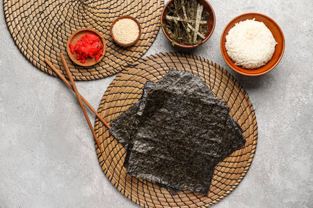 Wicker mat with nori sheets, ginger, rice and sesame seeds on grunge backgroundの写真素材