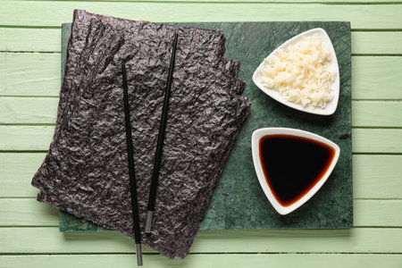 Slate board with nori sheets, sauce and rice on green wooden backgroundの写真素材