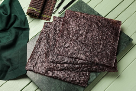 Board with nori sheets on color wooden background