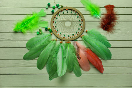 Dream catcher with beads and feathers on green wooden backgroundの写真素材