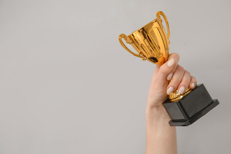 Woman with gold cup on gray backgroundの写真素材