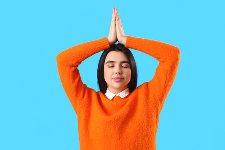 Young woman meditating on blue backgroundの写真素材