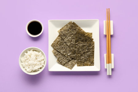 Plate with nori sheets, chopsticks, rice and soy sauce on color backgroundの写真素材