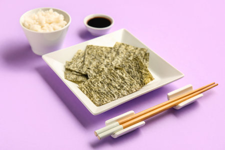 Plate with nori sheets, chopsticks, rice and soy sauce on color backgroundの写真素材