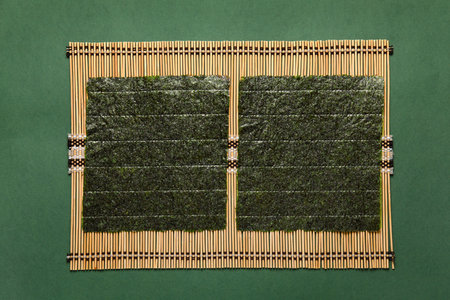 Bamboo mat with nori sheets on color backgroundの写真素材